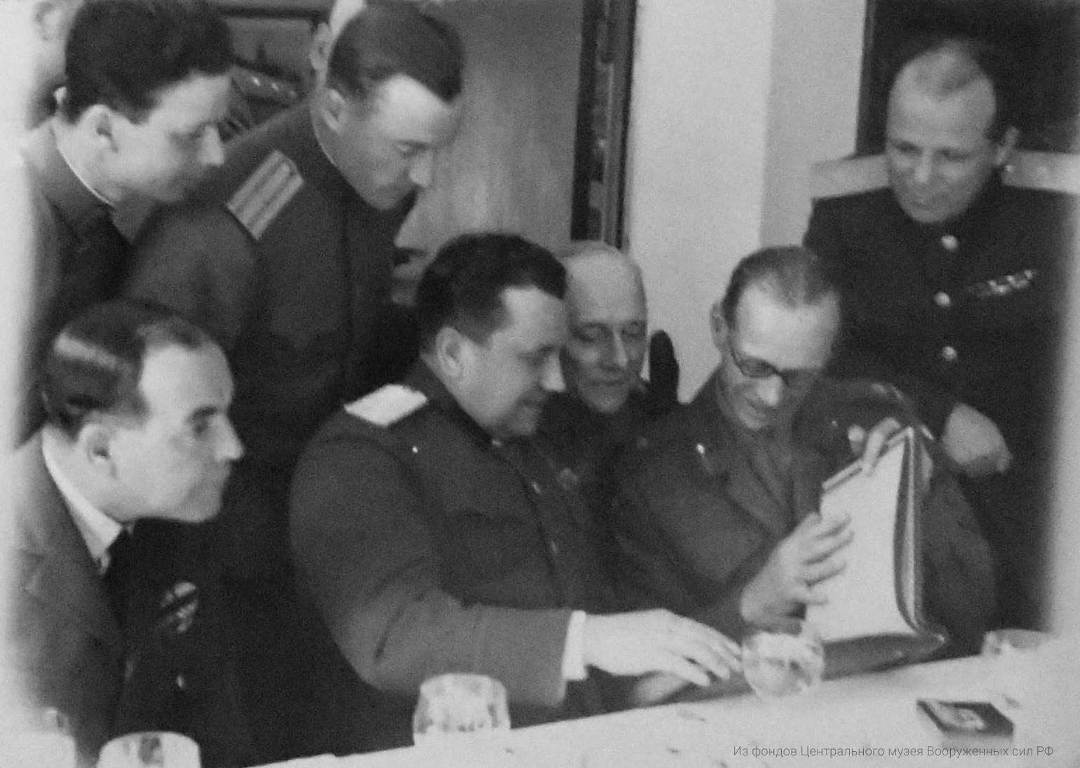 Командарм Гришин, генерал-лейтенант Сычев и генерал Дэмпсэй рассматривают альбом снимков дружеских встреч с союзниками, подарок командования 49 армии